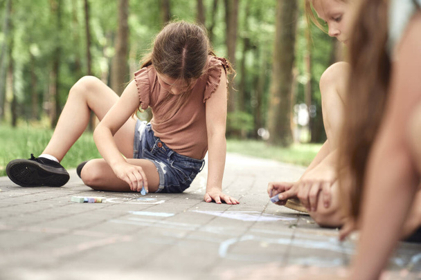 Група дітей, що розмальовують крейдою в літній день
  - Фото, зображення
