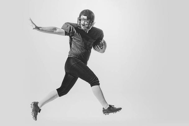 Attack and defense. Dynamic portrait of american football player in action and motion isolated on white background. Concept of sport, achievements, retro style. Monochrome - Фото, изображение