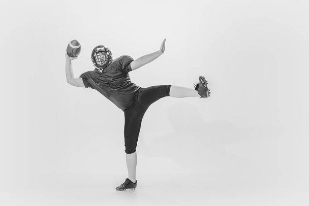 Powerful throw. Studio shot of american football player training with ball isolated on white background. Concept of sport, achievements, retro fashion style. Monochrome - Valokuva, kuva