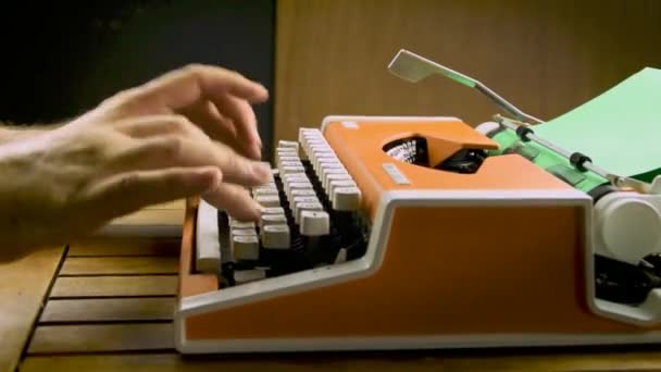 Male hands typing on a vintage typewriter. Old mechanical orange, white. Green paper. Table shaking trembling under the force of keystrokes. - Imágenes, Vídeo