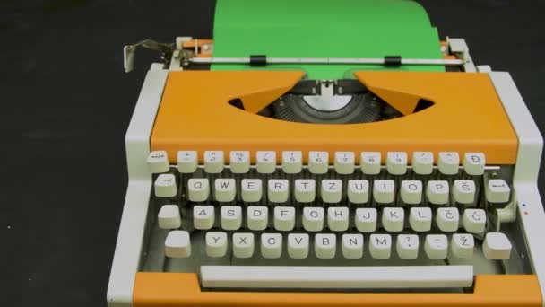 Typewriter stylish orange. Vintage mechanical typing machine. White keyboard green paper. Camera travelling above. - Footage, Video