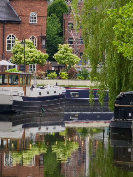 Narrowboat, trees and their reflections in the canal water in Castlefield inner city conservation in Manchester, UK - Zdjęcie, obraz