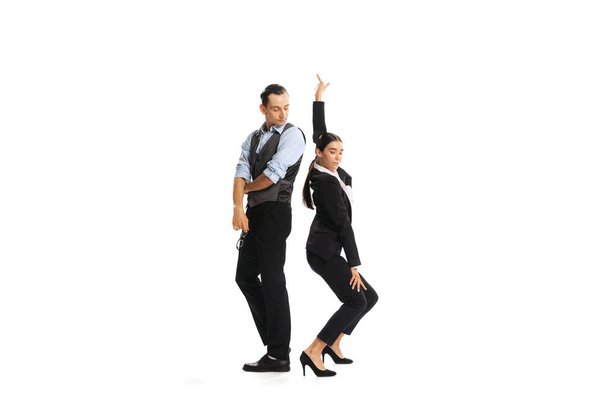 Portrait of two office workers, woman dancing near staring man isolated on white background. Office relationship. Concept of business, office lifestyle, success, ballet, career, expression, ad - Foto, afbeelding