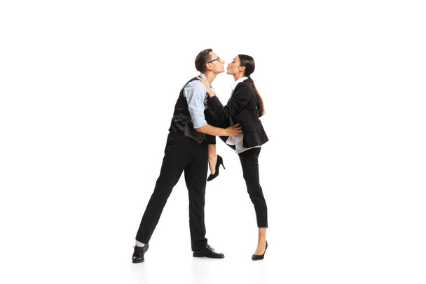 Portrait of two employees, managers in official suit kissing isolated over white background. Office romance. Concept of business, office lifestyle, success, ballet, career, expression, ad - Fotó, kép