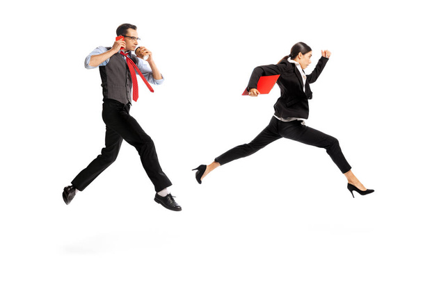 Portrait of two employees, man and woman being in a hurry isolated over white background. Being late for a meeting. Concept of business, office lifestyle, success, career, expression, ad - Foto, afbeelding