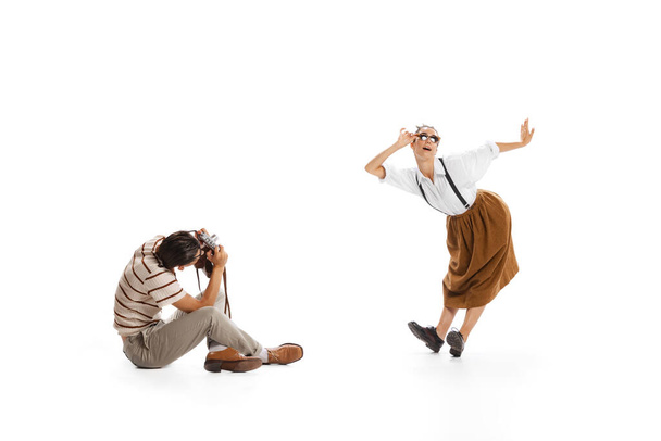 Portrait of man taking photo of beautiful stylish woman in a jump isolated on white background. Retro style. Concept of business, office lifestyle, success, ballet, career, expression, ad - Photo, Image