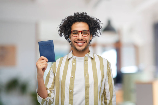 documents and people concept - smiling man with passport over office background - Fotó, kép