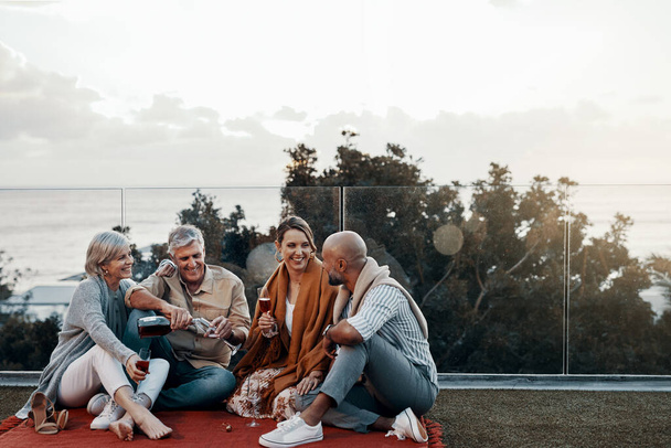 Time to relax with some wine in hand. Full length shot of an affectionate family having wine together while celebrating a new year outdoors - Foto, imagen