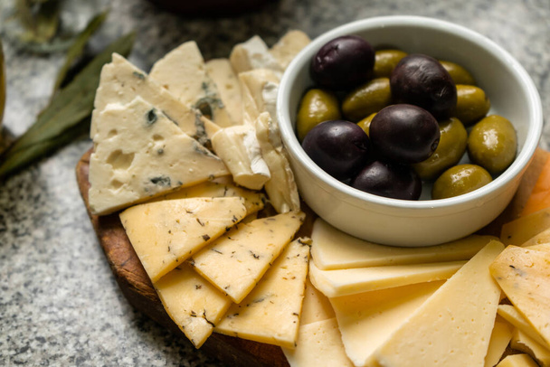 Разнообразие сыров с зелеными и черными оливками - Фото, изображение