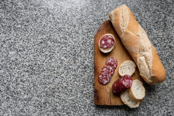 Вид зверху салямі з нарізаним хлібом на мармуровому стільниці
 - Фото, зображення