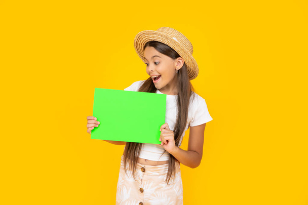 shocked teen girl with copy space on green paper on yellow background. - Foto, afbeelding