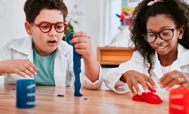 This is what we call a stretch of the imagination. two adorable school pupils playing and experimenting with slime in science class at school - Foto, Imagen
