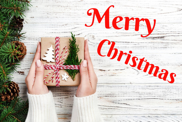 Merry Christmas text. Christmas gift box wrapped in recycled paper, with ribbon bow, with ribbon on rustic vintage background. Holiday concept. - 写真・画像
