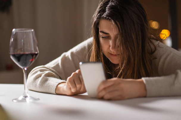 alcoholism, alcohol addiction and people concept - drunk woman or female alcoholic with smartphone drinking red wine at home - Fotografie, Obrázek