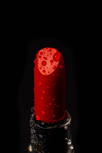 Close up red lipstick with water droplets. Vertical shot black background. - Foto, imagen