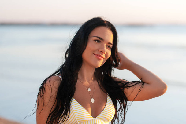 mensen, zomer en zwemkleding concept - vrolijke glimlachende jonge vrouw in bikini badpak op strand - Foto, afbeelding