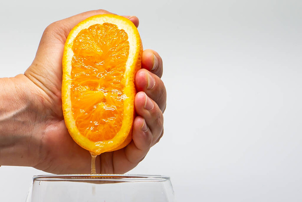 Macro photo of an orange squeezed with a hand. Orange juice. Side photo. Citrus fruit juice. Natural juices. - Foto, afbeelding