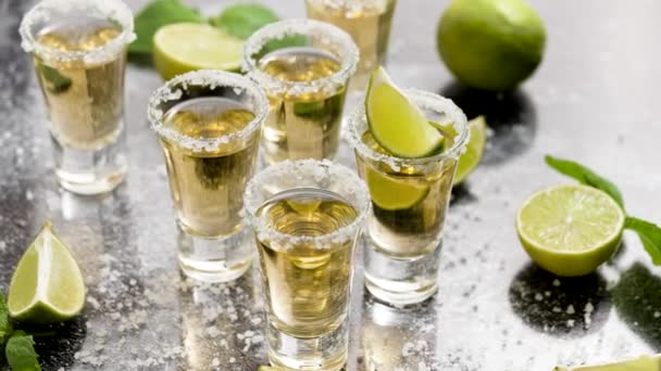 Golden Tequila shots served with lime and sea salt on table, flat lay. - Video