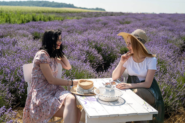 Happy sisters looking at lavender flowers in big field - Photo, Image