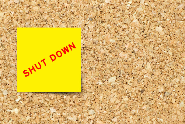 Yellow note paper with word shut down on cork board background with copy space - Fotoğraf, Görsel