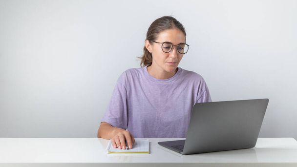 女性の学生はノートパソコンとペンで座っています。高品質の写真 - 写真・画像