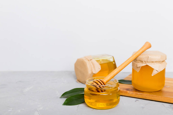 Miel en tarro con hojas y tarro de miel sobre fondo de color vista superior con texto de copia. - Foto, imagen