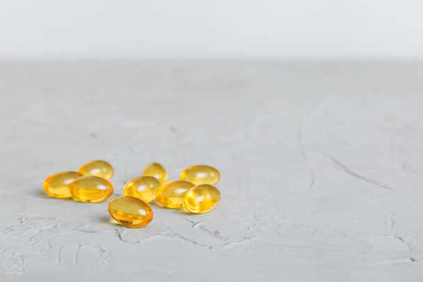 Cod liver oil omega 3 gel capsules on colored background with copy space. Heap of Omega 3 soft gel capsules. - Fotografie, Obrázek