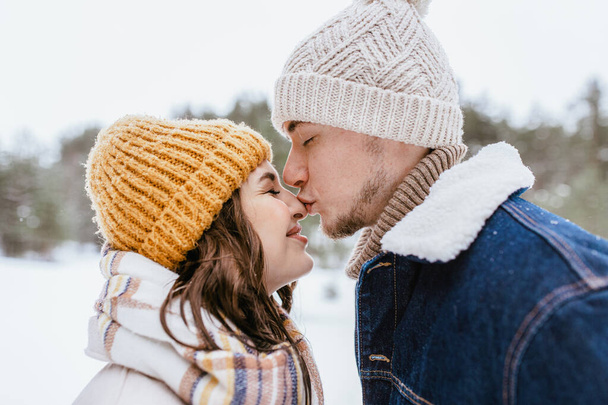 people, love and leisure concept - happy man kissing womans nose in winter forest - Fotografie, Obrázek