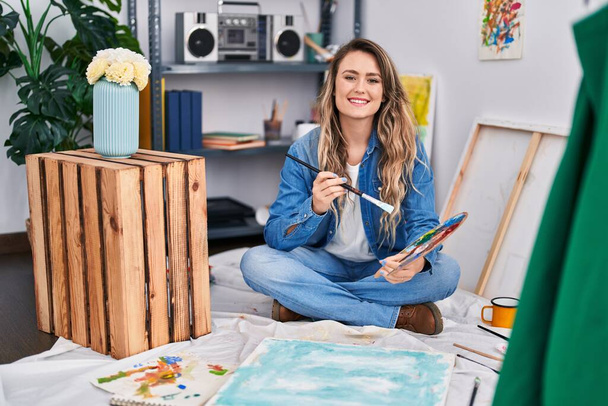 Young woman artist drawing sitting on floor at art studio - Foto, imagen
