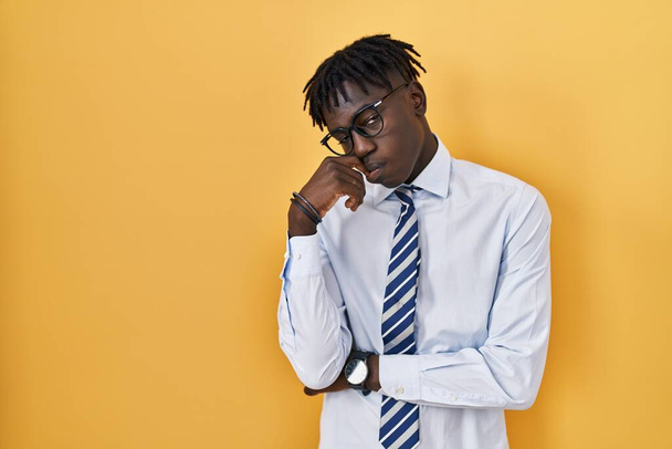 African man with dreadlocks standing over yellow background looking stressed and nervous with hands on mouth biting nails. anxiety problem.  - Photo, Image