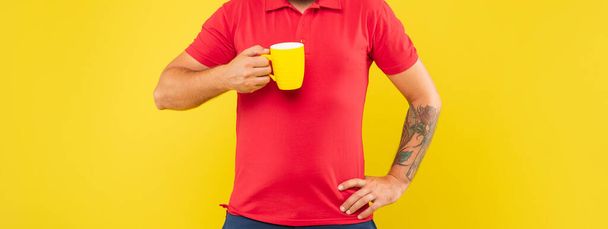 Man crop view holding mug keeping arm akimbo yellow background, tea. - Φωτογραφία, εικόνα