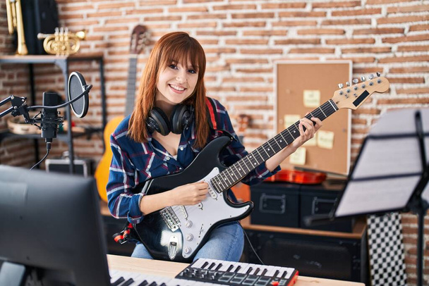 Mujer joven músico cantando canción tocando la guitarra eléctrica en el estudio de música - Foto, imagen