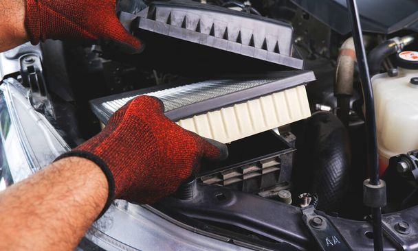 Car air filter being inserted into air filter box in the automobile engine compartment by auto mechanic, Automobile maintenance service business concept - Photo, image