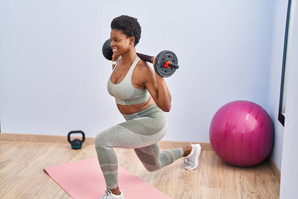Femme afro-américaine souriant jambes d'entraînement confiantes exerce au centre sportif - Photo, image