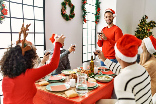 Gruppo di giovani sorridenti felici di avere la cena di Natale e di parlare brindisi a casa. - Foto, immagini