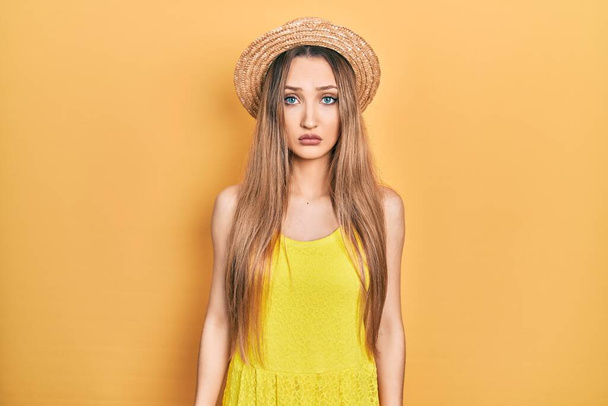 Fiatal szőke lány visel nyári kalap depressziós és aggódni a szorongás, sír dühös és fél. szomorú kifejezés.  - Fotó, kép