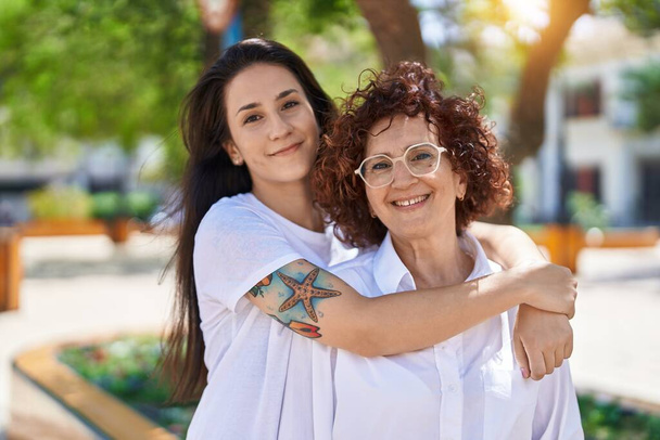Two women mother and daughter hugging each other at park - Фото, изображение