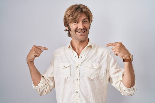 Middle age man standing over isolated background looking confident with smile on face, pointing oneself with fingers proud and happy.  - Photo, Image