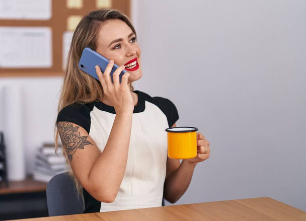 Young beautiful hispanic woman business worker talking on smartphone drinking coffee at office - Zdjęcie, obraz