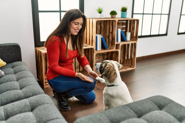 Young woman smiling confident teaching dog at home - 写真・画像