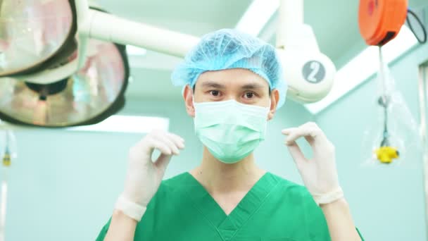 Retrato de cirujano asiático con máscara médica de pie en quirófano en un hospital. Equipo de cirujanos profesionales. Atención médica, concepto de servicio médico de emergencia - Imágenes, Vídeo