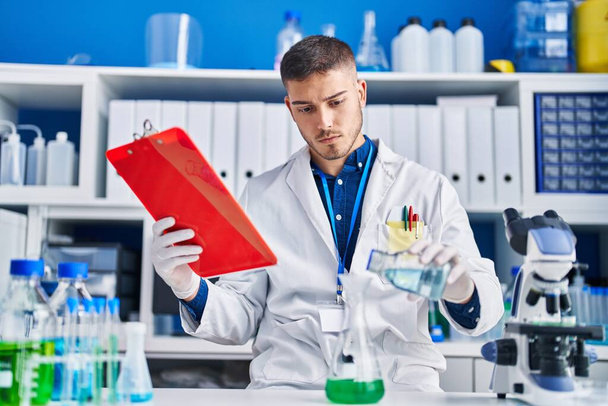 Joven científico hispano midiendo líquido en laboratorio - Foto, imagen