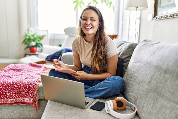 Young hispanic girl having online class sitting on the sofa at home. - Photo, Image