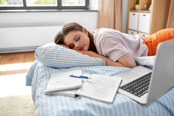 school, education and laziness concept - tired teenage student girl with laptop computer and notebooks sleeping on bed at home - Foto, Imagem