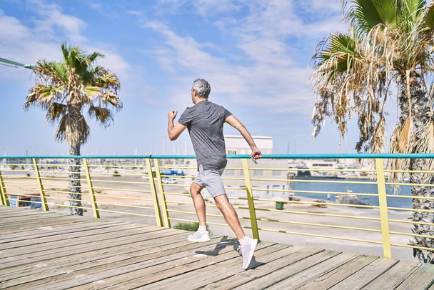 Hombre hispano de mediana edad usando ropa deportiva corriendo por la calle - Foto, Imagen