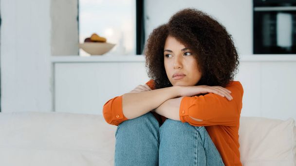 Samotna, samotna, zestresowana Afroamerykanka siedząca ze smutnym problemem na kanapie w domu myśląca o problemach odwracając wzrok od złego zdrowia sfrustrowana dziewczyna czująca się źle smutek nie podejmuje złej decyzji - Zdjęcie, obraz