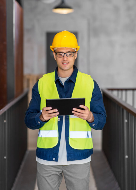 architecture, construction business and building concept - happy smiling male architect in helmet and safety west with tablet pc computer at office - Фото, изображение