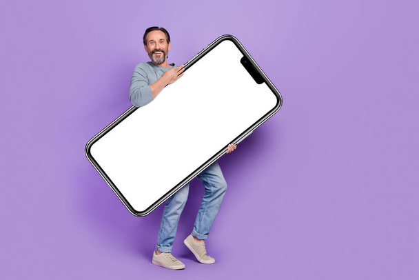 Full body photo of mature man promoter hold hands banner promo isolated over violet color background. - Foto, immagini