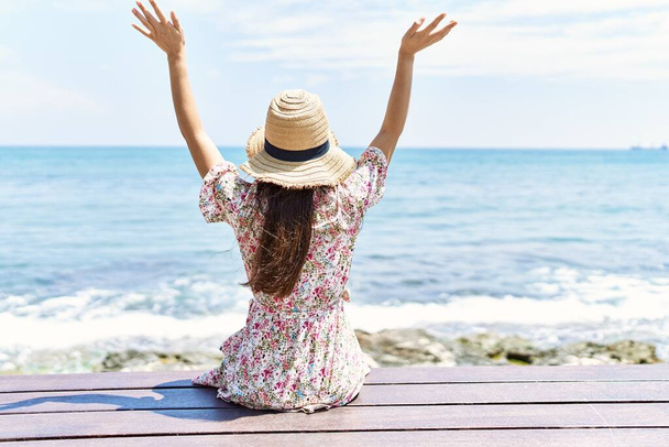 Plajda bankta oturan, yaz şapkası takan genç Latin kız.. - Fotoğraf, Görsel