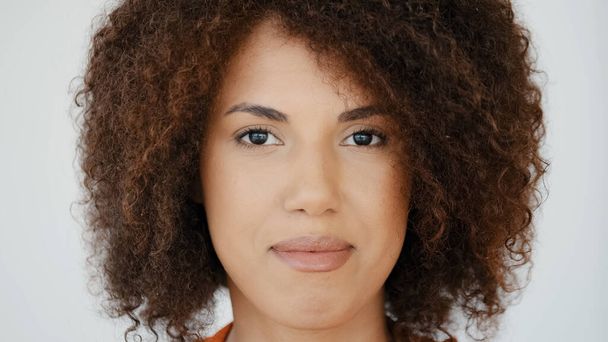 Extreme close up headshot female serious calm face with perfect skin natural make-up African biracial model woman with curly hair looking at camera sad expression discrimination upset. Girl portrait - Fotoğraf, Görsel